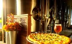 An Oktoberfest “Field Party Festbier” with a CPR craft pizza shown in front our Brig…